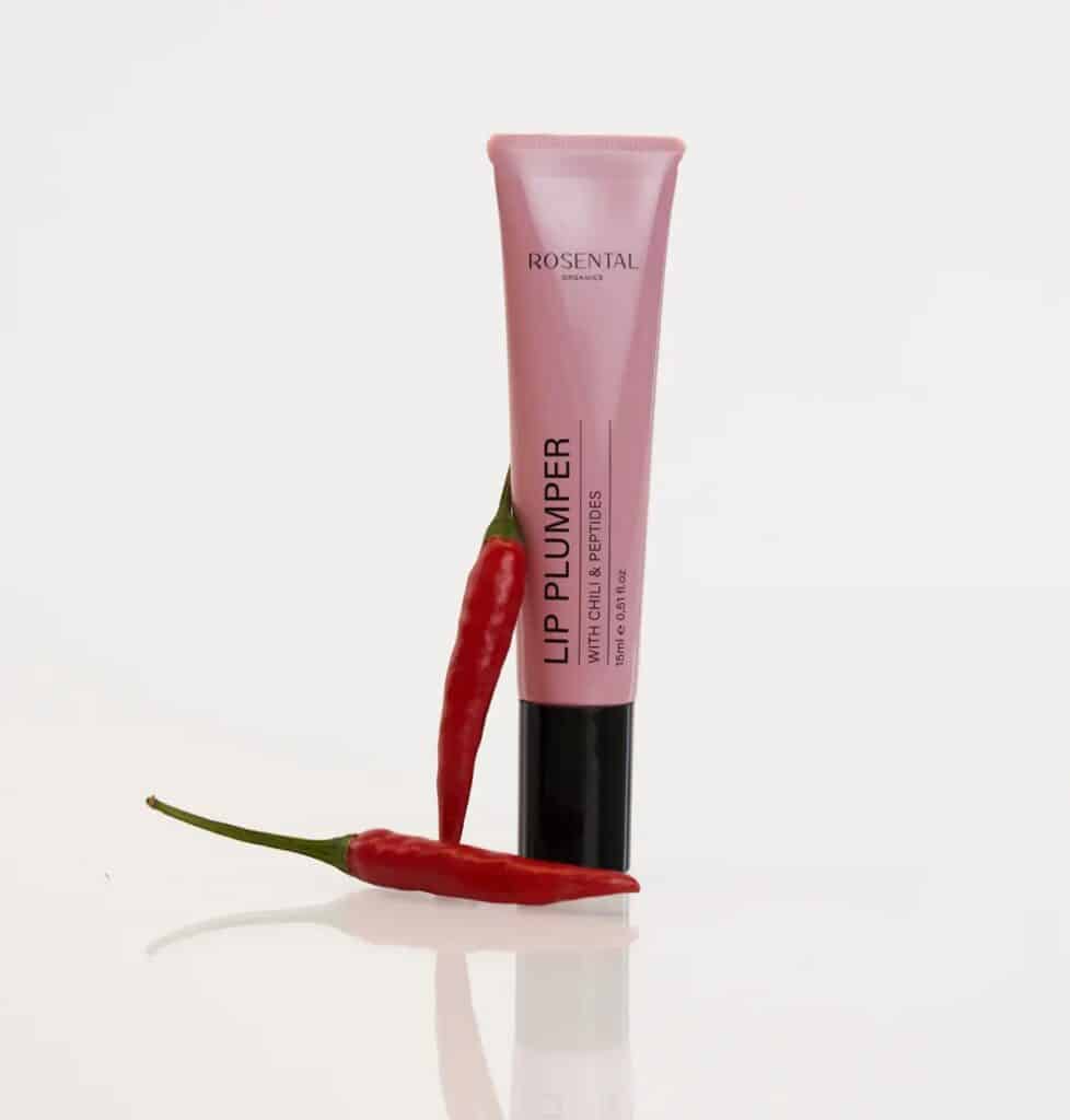 Rosental Lip Plumper Tube, umgeben von roten Chilischoten als Symbol für die natürlichen, durchblutungsfördernden Wirkstoffe.